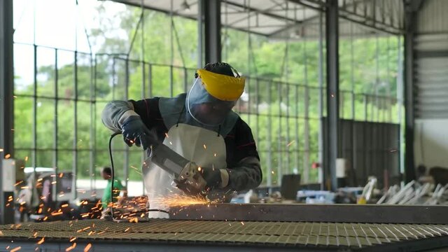 Worker wearing PPE griding metal frame