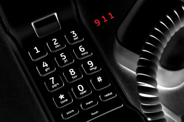 Ominous Concept of calling 911 with black phone and lit keys.  911 in red.