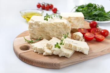 Tasty healthy sheep or goat feta cheese. Chunks of cheese on a wooden board on white background.