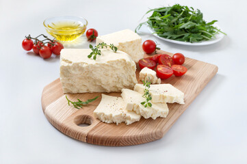Fototapeta na wymiar Tasty healthy sheep or goat feta cheese. Chunks of cheese on a wooden board on white background.