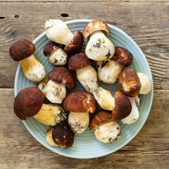 Porcini mushrooms in blue plate on old wooden background, top view