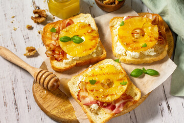 Healthy breakfast or snack, snacks. Toast with caramelized pineapple, bacon, nuts, and ricotta on the kitchen table.