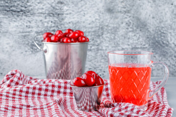 Dogwood berries in buckets with drink, picnic cloth side view on plaster and grungy background
