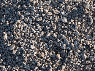 Texture of a placer of small rock stones illuminated by the low early sun.