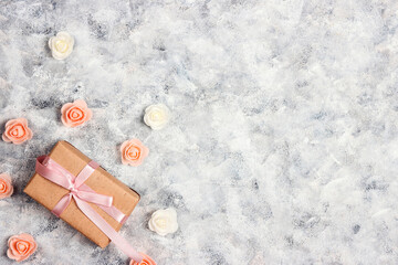 Gift box with small rose flowers on gray canvas background.