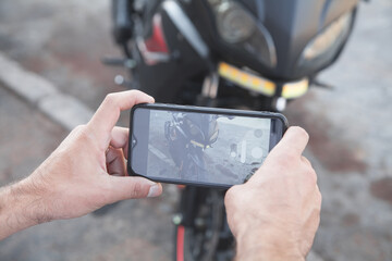 Man taking photo of a motorcycle on his phone.