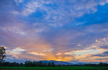 Obraz na płótnie Canvas beautiful warm colorful sunrise or stunning sunset at a large mountain, with green rice field scenery in summer farming time, Asian county, or agriculture countryside. landscape background texture.