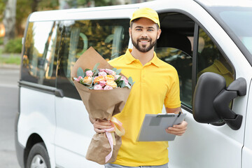 Delivery man with bouquet of beautiful flowers near car outdoors