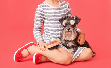 Little girl brushing hair of her dog on color background