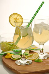 Refreshment Summer drink. Lemonade with ice in fancy glass with straw, there are lemons and a half near glass. concept of relaxing during the heat in the bar.