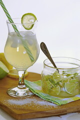 Refreshment Summer drink. Lemonade with ice in fancy glass with straw, there are lemons and a half near glass. concept of relaxing during the heat in the bar.