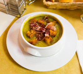 Vegetable zucchini cream soup with croutons and bacon served in ceramic bowl