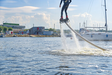 man having fun on Flyboard. Flyboarding in a sunny summer day at river in harbor. Extrime water activity flyboard.