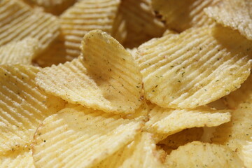 Background corrugated golden chips with texture. Potato chips is snack, ready to eat and fat food or junk food. Horizontal. Top view.