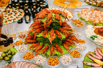 Different food cooked on the wooden table crayfish, squid, seafood. Alcohol and food. Beer with snacks on the table. Indoors Food Concept.