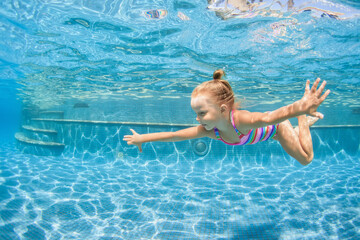 Funny portrait of child learning swimming, dive in blue pool with fun - jumping deep down...