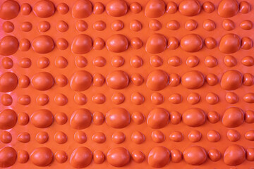 Orange orthopedic mat in the form of small stones on a white background for foot massage. Prevention of children's flat feet