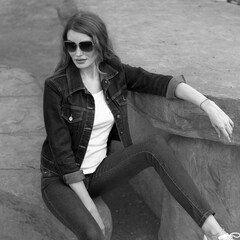 Style of a girl model sitting on a stone bench Photo in black and white style.