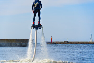 man having fun on Flyboard. Flyboarding in a sunny summer day at river in harbor. Extrime water activity flyboard.