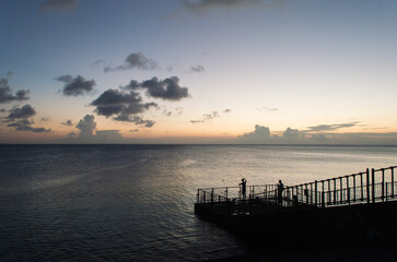 Obraz premium オレンジ色の夕焼けとシルエットの釣り人