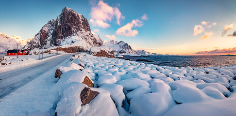 Colorful winter sunrise on Hamnoy village, Lofoten Islands. Fresh snow covered stones on the shore...