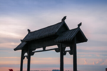 The roof of the gate in Chinese style against the background of the sunset sky