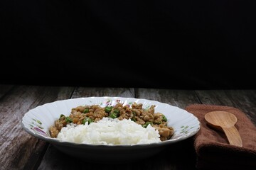Traditional fried and stirred minced or marinated pork with cutting green bean serving with cooked jasmine rice on the plate. Famous Thai spicy food in Asia restaurant. 
