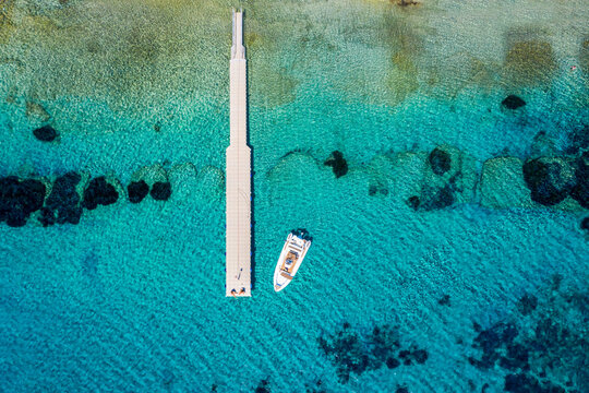 A floating pier with a rib boat over the turquoise, clear sea of the Aegean Sea in Greece during summer time