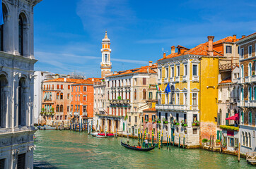Grand Canal waterway in Venice historical city centre with sailing gondola, Palazzo Civran palace, colorful buildings and Church Holy Apostles of Christ bell tower. Veneto Region, Northern Italy.