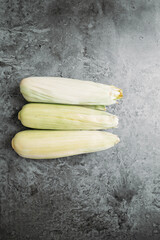 Top view of fresh sweet corn cob with copy space on concrete textured background