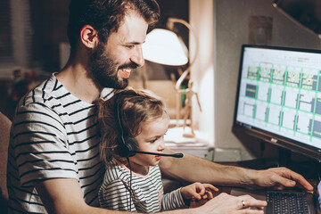 Father and daughter are working on a laptop. businessman working from home and watching the child. A young man works on a computer. Launch. Freelancer concept. Family on quarantine