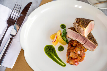 Close up view of medium rare tuna steak, grilled in herb crust and served with vegetables ragu
