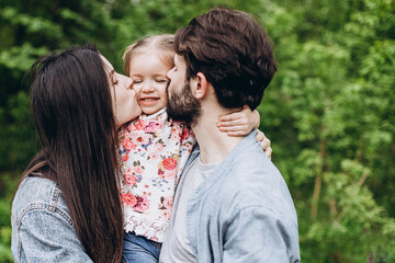 Fototapeta premium Happy stylish family: Photo of a young family enjoying a vacation in a park in a spring countryside