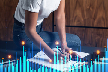 Businesswoman taking notes using smart-phone. Financial graph and chart hologram double exposure.
