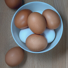 several fresh chicken eggs in a ceramic cup on a wooden background. Healthy eating concept