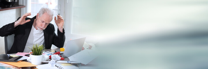 Overworked businessman sitting at a messy desk; panoramic banner