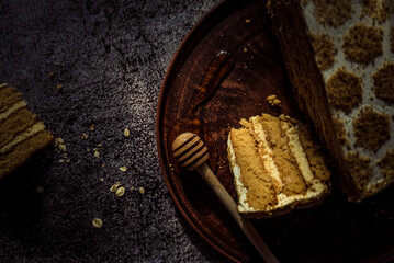 piece of honey cake, honey on a large clay plate on a gray background