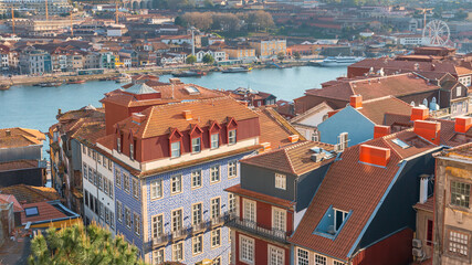 top view of the red tiled roofs of the Portuguese city of Porto in the background of the river with vintage boats