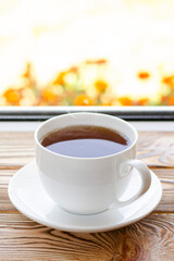 A cup of tea stands on a window sill against the window