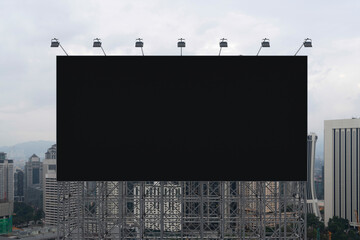 Blank black road billboard with Kuala Lumpur cityscape background at day time. Street advertising poster, mock up, 3D rendering. Front view. Concept of marketing to promote or sell services or ideas.