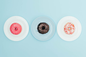 Different bright donuts on a plate on a blue background.