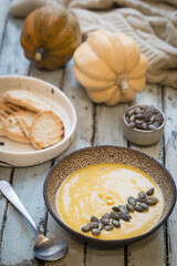 Seasonal autumn food. Healthy Pumpkin soup with cream and organic pumpkin seeds.