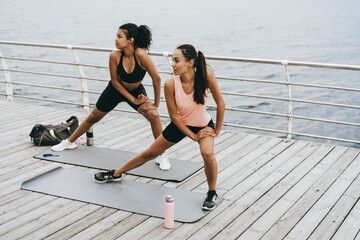 Image of multinational sportswomen doing exercise while working out