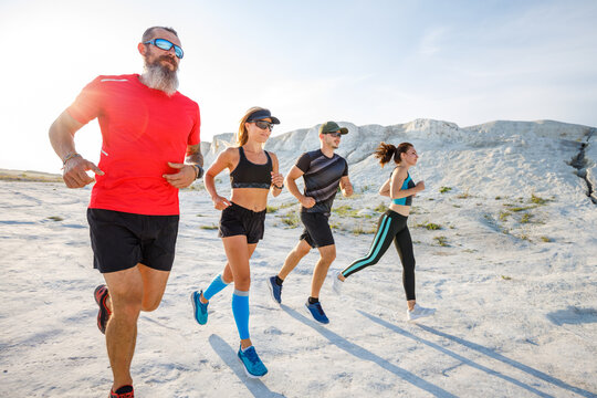 Four Fit Runners Jogging Together In Desert