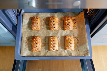 food cooking, culinary and pastry concept - baking tray with jam pies in oven at home kitchen