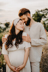 young authentic couple in love man and woman dressed in linen clothes are photographed at sunset standing between beds of wildflowers on a flower farm, selective focus, noise effect
