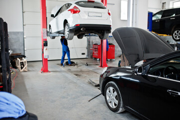 Cars lifting in maintenance at garage service station.