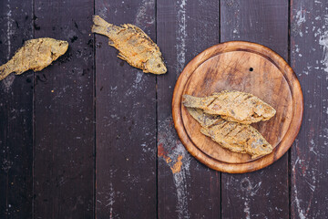 photo of small fried breaded fish in a pan on a wooden board with space for your text