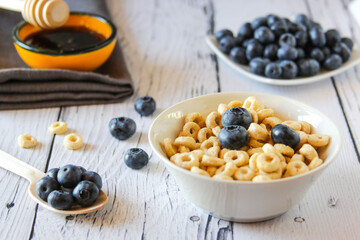 Honey rings with blueberries and honey in a bowl on the table wooden background. Copy space. Top view. Flat lay. Horizontal orientation.