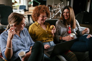 Girlfriends talking and laughing in office. Beautiful women drinking coffee in the office.